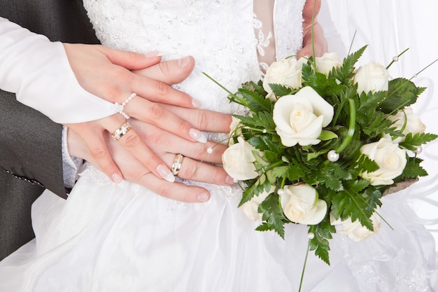 Handen van bruid en bruidegom met ringen en bruidsboeket