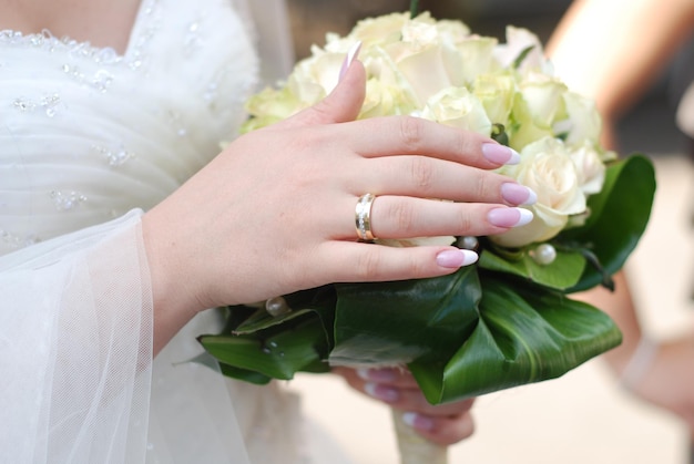 Handen van bruid met huwelijksboeket met rozen