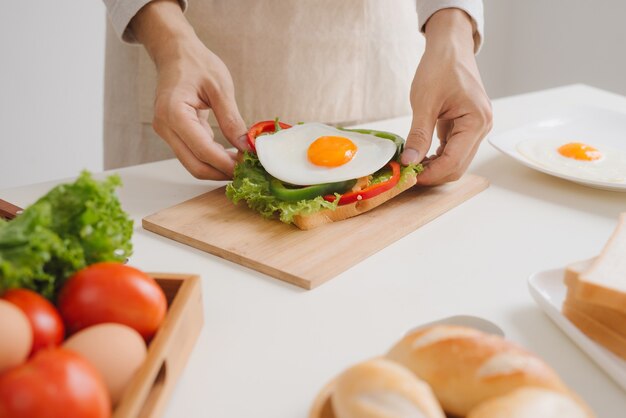 Handen van de mens bereiden ontbijt met sandwich met gepocheerde eieren