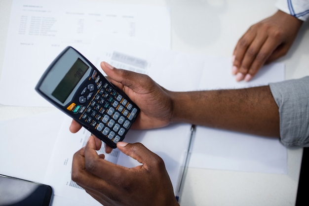 Handen van de mens die een calculator gebruiken