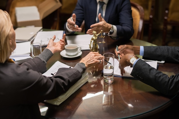 Handen van drie hedendaagse advocaten tijdens discussie