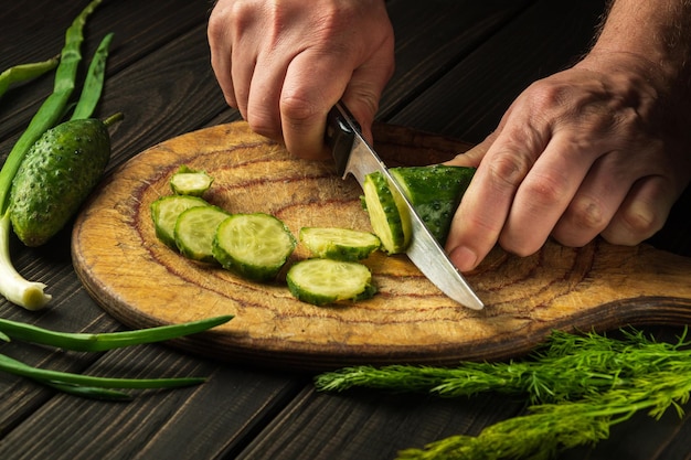 Handen van een chef-kok met een mes tijdens het koken in de keuken van een restaurant