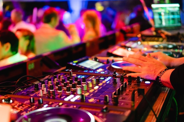 Handen van een DJ met een controller die musical speelt op een professionele draaitafel voor een feestje