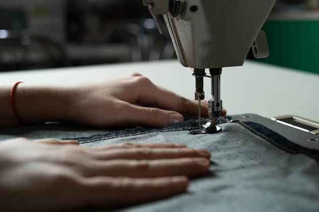 Handen van een jong meisje aan de naaimachine in de werkplaats Naaien volgens het schema van de auteur Naaiatelierconcept Ruimte kopiëren