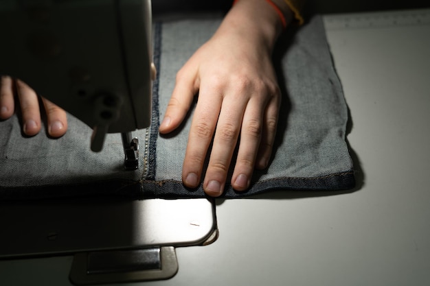 Handen van een jong meisje in een naaiatelier Naaien op een rits op een naaimachine Naaiconcept Plaats voor uw tekst