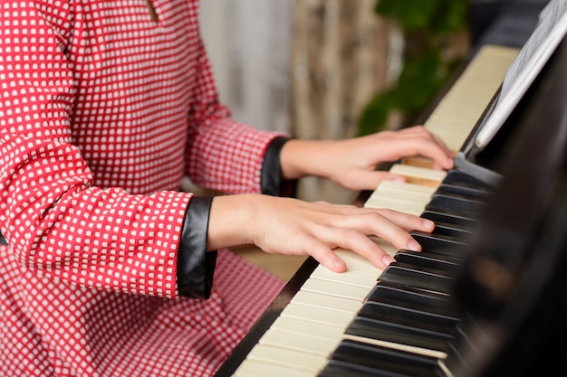 Handen van een jong vrouwelijk kind die klassieke muziek thuis uitvoeren