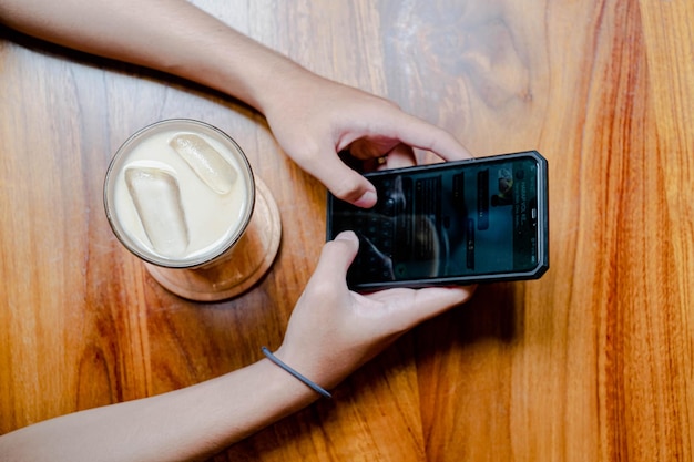 Handen van een jonge man die op een telefoon typt in café