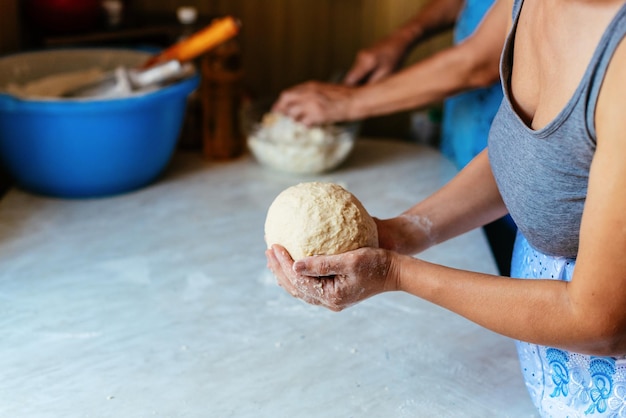 Handen van een jonge vrouw die deeg kneedt om thuis brood of pizza te maken Productie van meelproducten Het maken van deeg door vrouwelijke handen
