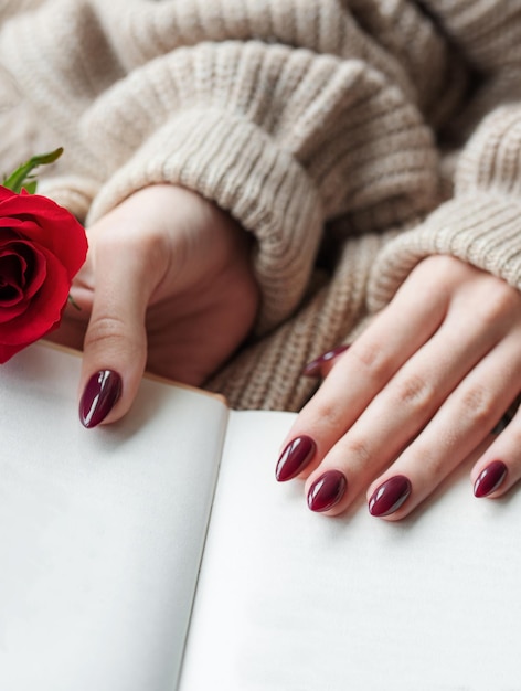 Handen van een jonge vrouw met donkerrode manicure op nagels