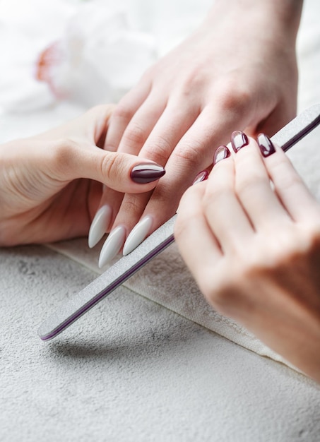 Handen van een jonge vrouw met witte manicure op nagels