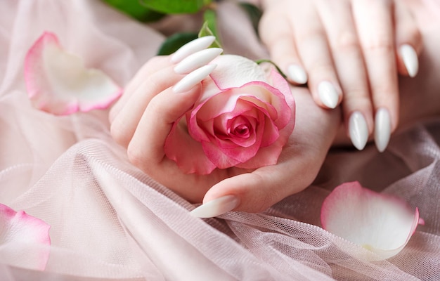 Handen van een jonge vrouw met witte manicure op nagels