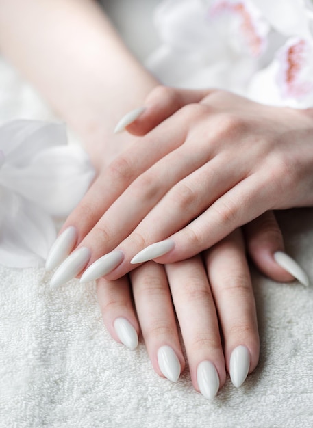 Handen van een jonge vrouw met witte manicure op nagels