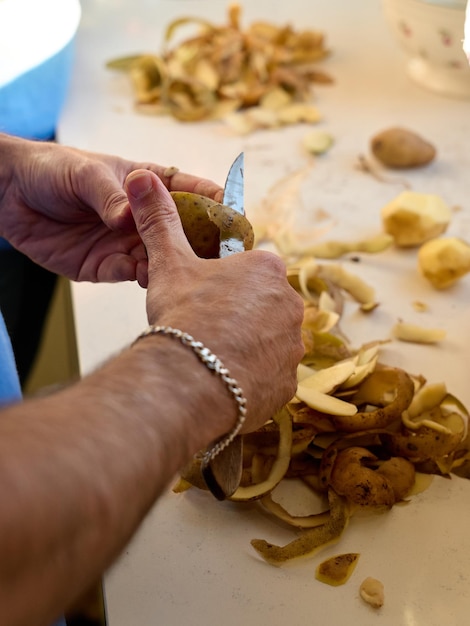 Handen van een man die aardappelen schilt zijn geen gezichten te zien