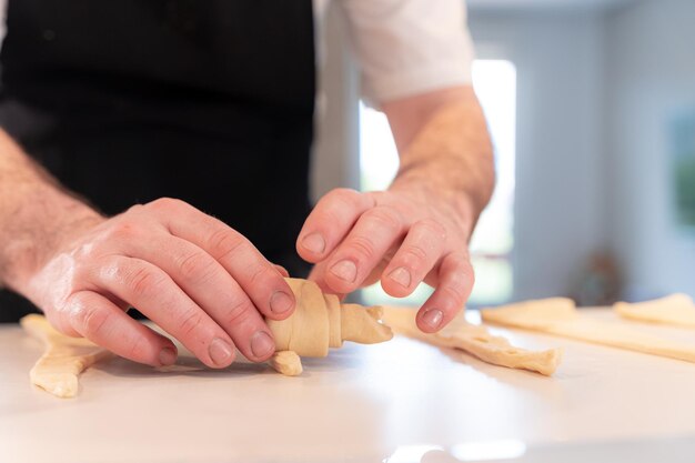 Handen van een man die croissants kookt met het bladerdeegwerk thuis