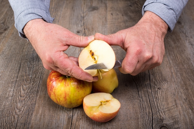 Handen van een man die een appel snijdt