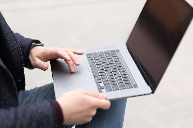 Handen van een man in de buurt van het toetsenbord van de laptop werken buitenshuis