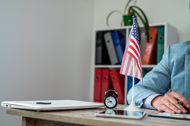 handen van een man in een pak achter een tafel met een Amerikaanse vlag erop zakelijke zakelijke stijl