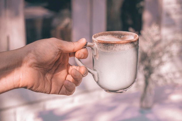 Handen van een man of barista met een kop warme koffie latte met hartvormige schuimkunst