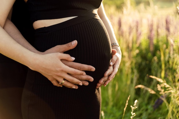 handen van een man omhelzen de buik van een zwangere vrouw bijgesneden foto zwangerschap en gelukkig gezin concept