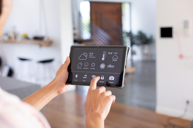 Handen van een man van twee rassen thuis met een tablet met een slimme thuisinterface op het scherm. Communicatie, technologie en concept van het huiselijk leven.