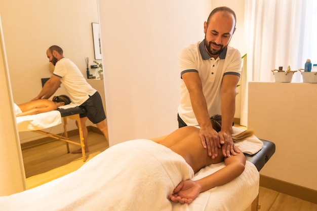 Handen van een masseur die een massage op tafel uitvoert voor een klant op de rug