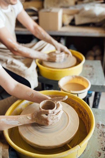 Handen van een pottenbakker die een keramische pot maakt op het aardewerkwiel