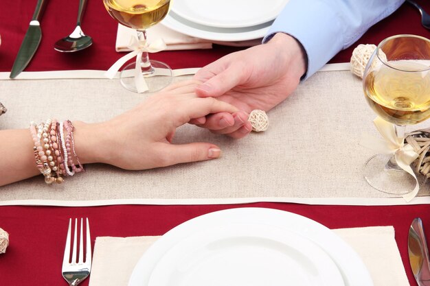 Handen van een romantisch stel boven een restauranttafel