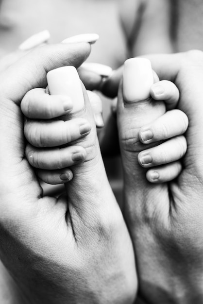 Handen van een slapende pasgeborene in de handen van de moeder close-up Kleine vingers van een pasgeborene die de duimen van de hand van de moeder vasthoudt Studio macrofotografie Concepten van familie en liefde Zwart wit