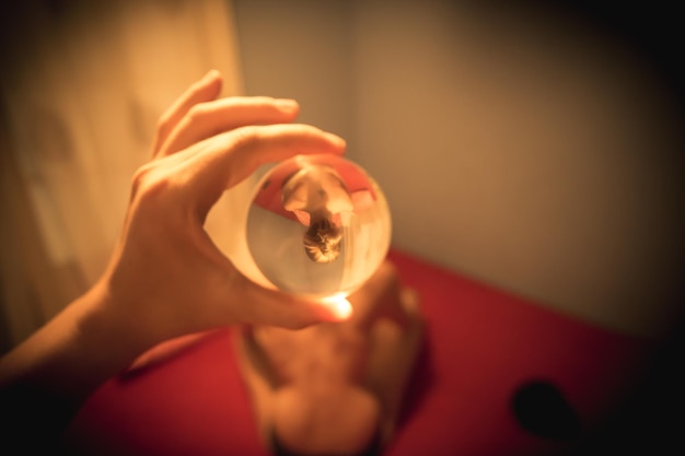 handen van een vrouw die een kristallen bol vasthoudt die het beeld van de voorkant weerspiegelt
