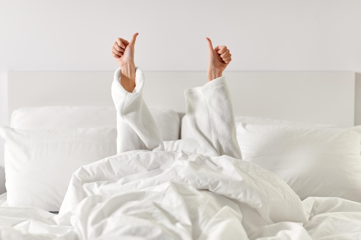 Foto handen van een vrouw die in bed ligt en duimen omhoog toont
