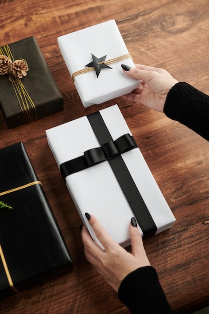 Handen van een vrouw die versierde geschenken op tafel legt, klaar om het naar klanten te sturen