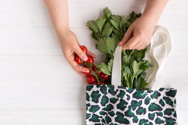 Handen van een vrouw halen verse biologische tomaten uit Eco Shopping Bag met trendy luipaardpatroon print op houten achtergrond Flat Lay Top View