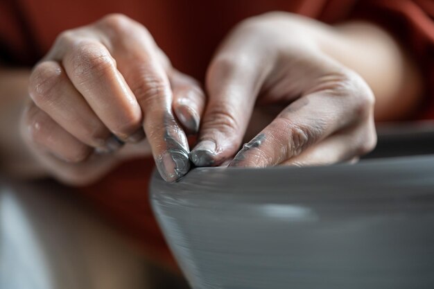 Foto handen van een vrouwelijke ondernemer die met klei werkt bij de vervaardiging van potten voor interieurdecoratie