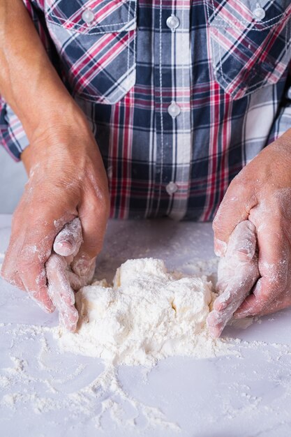 Handen van grootmoeder en jonge jongen, kleinzoon koken, deeg kneden, taart bakken, cake, koekjes. Familie tijd in de gezellige keuken. Activiteit thuis.