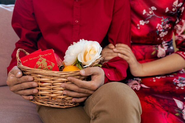 Handen van jong stel met mand met bloemen en ansichtkaart