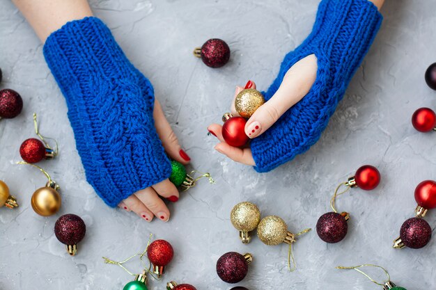 Handen van jonge mooie vrouw die in blauwe vuisthandschoenen Kerstmisballen houden