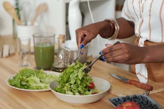 Foto handen van jonge vrouw die verse saladeingrediënten mengt