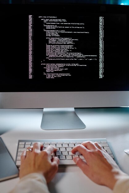 Handen van jonge vrouwelijke programmeur typen op toetsenbord tijdens het decoderen van gegevens