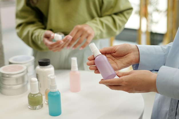 Handen van jonge vrouwelijke shopper met plastic fles met sproeier