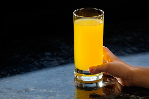 Handen van kind met glas met jus d'orange