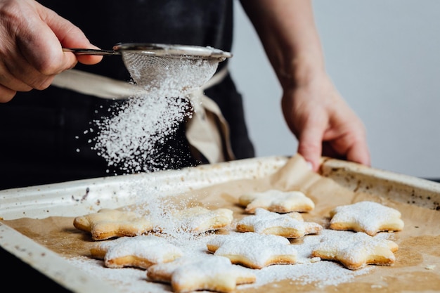 Handen van kok die poedersuiker toevoegen aan koekjes als topping