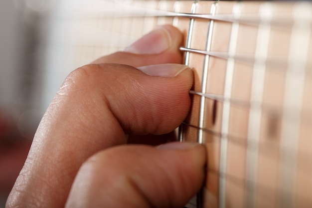 Foto handen van man elektrische gitaar spelen. vingers op tekenreeksen close-up. macro