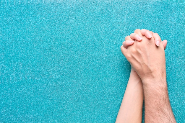 Handen van man en vrouw verenigd met vingers verweven paar op glitter aquamarijn achtergrond