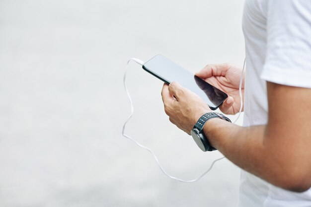 Handen van man luisteren naar muziek via applicatie op smartphone