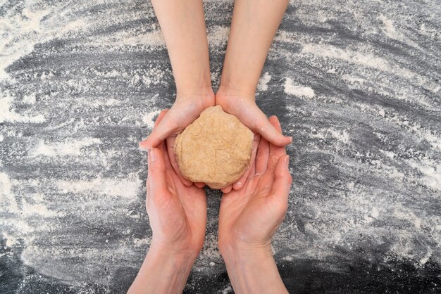 Handen van moeder en kind zijn met deeg. Koekjes koken met kinderen, samen tijd doorbrengen. Bovenaanzicht.