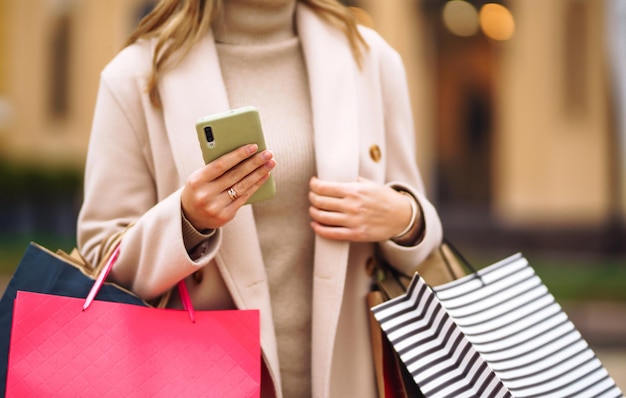 Handen van mooie vrouw met telefoon en een creditcard. Jonge vrouw met boodschappentassen.