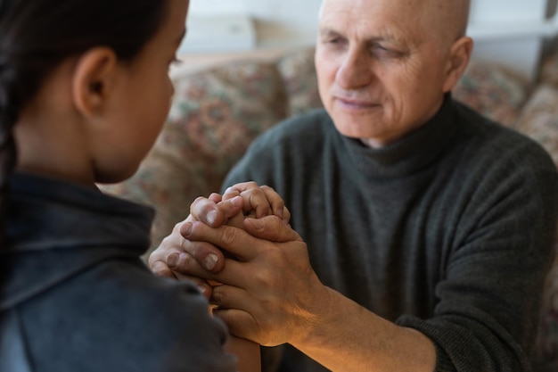 Handen van opa en kleindochter met gebed