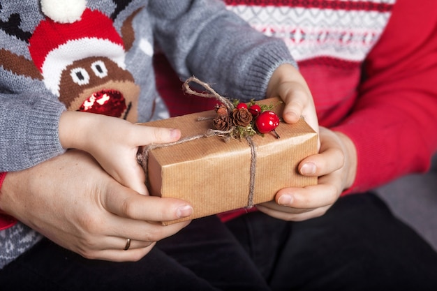 Handen van ouder en kind die een doos van de Kerstmisgift houden.