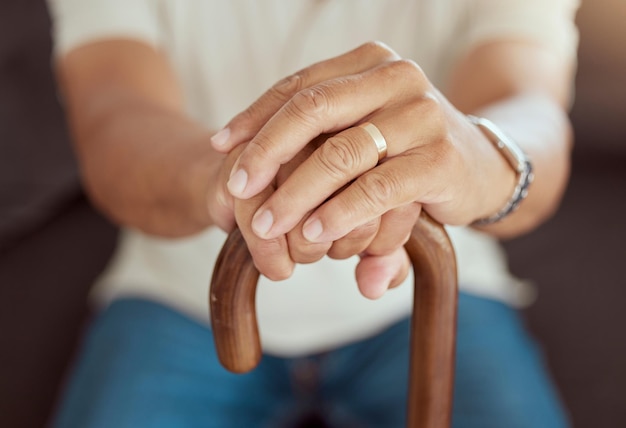 Handen van oudere man met een stok voor hulp, ondersteuning en hulp bij het lopen terwijl u ontspant op de bank in de woonkamer Trouwring hand van senior weduwe en gepensioneerde persoon zittend op de bank met wandelstok