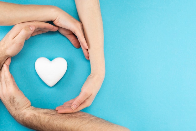 Handen van ouders en een kind omringen een wit hart op een blauwe achtergrond